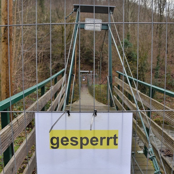 Es ist die abgesperrte Brücke mit einem Schild auf dem „gesperrt “ steht zu sehen.