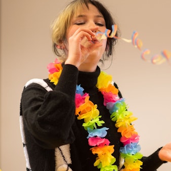 Elena Pintus mit einer bunten Blumenkette um den Hals und Luftschlangen.