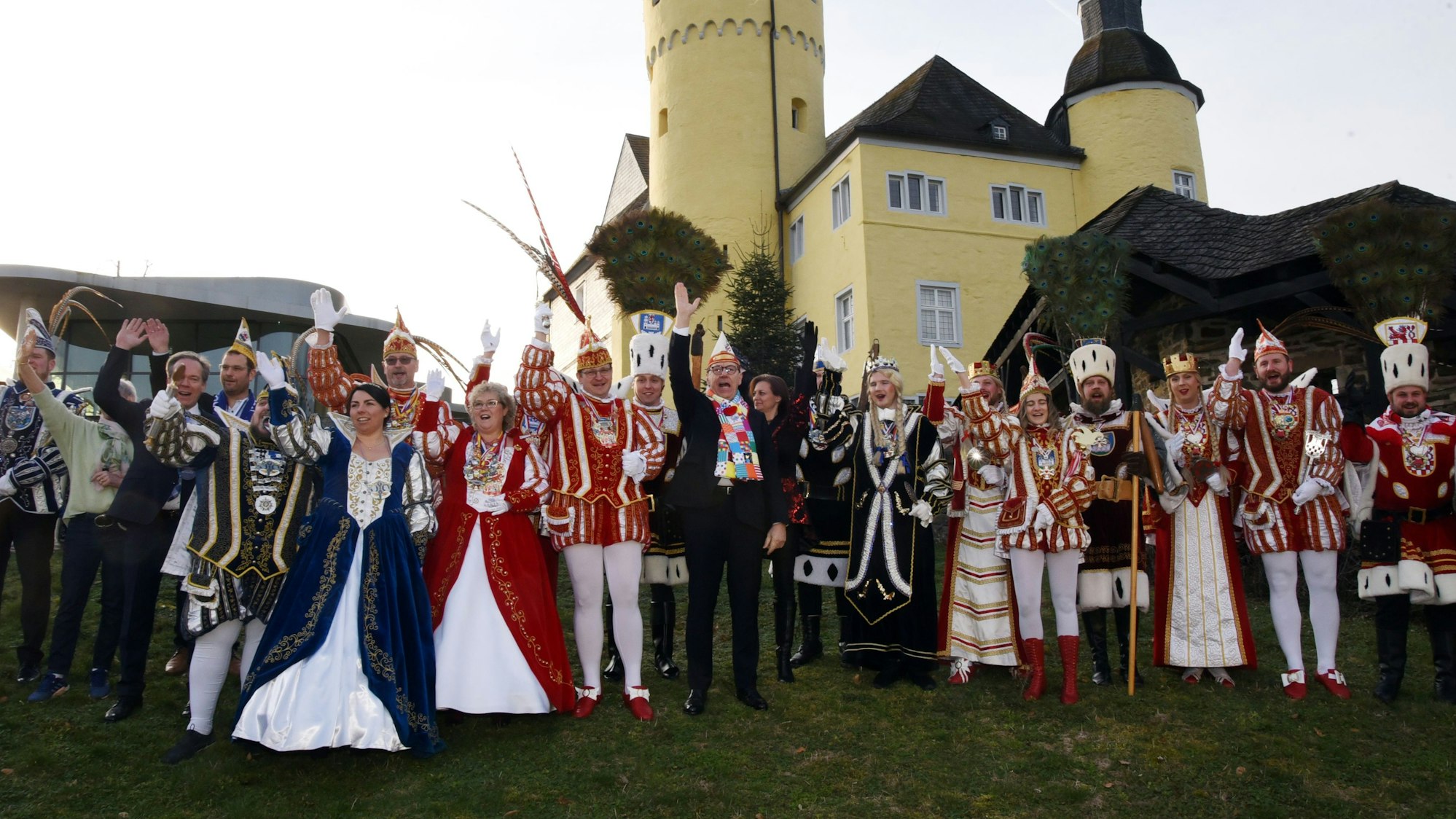 Zahlreiche Karnevals-Dreigestirne und Prinzenpaare stehen vor einer Schlosskulisse als Gruppe zusammen.
