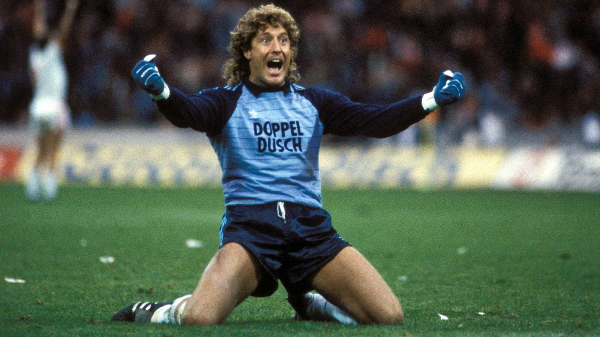 Toni Schumacher jubelt auf den Knien und schreit seine Freude heraus.