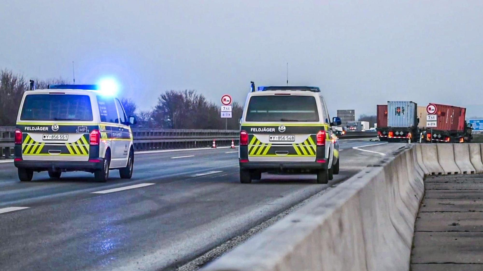 Die Feldjäger der Bundeswehr sperren einen Autobahnabschnitt nach einem Unfall eines US-Militärkonvois ab. Es ist Blaulicht zu sehen, im Hintergrund die kollidierten Lkw.