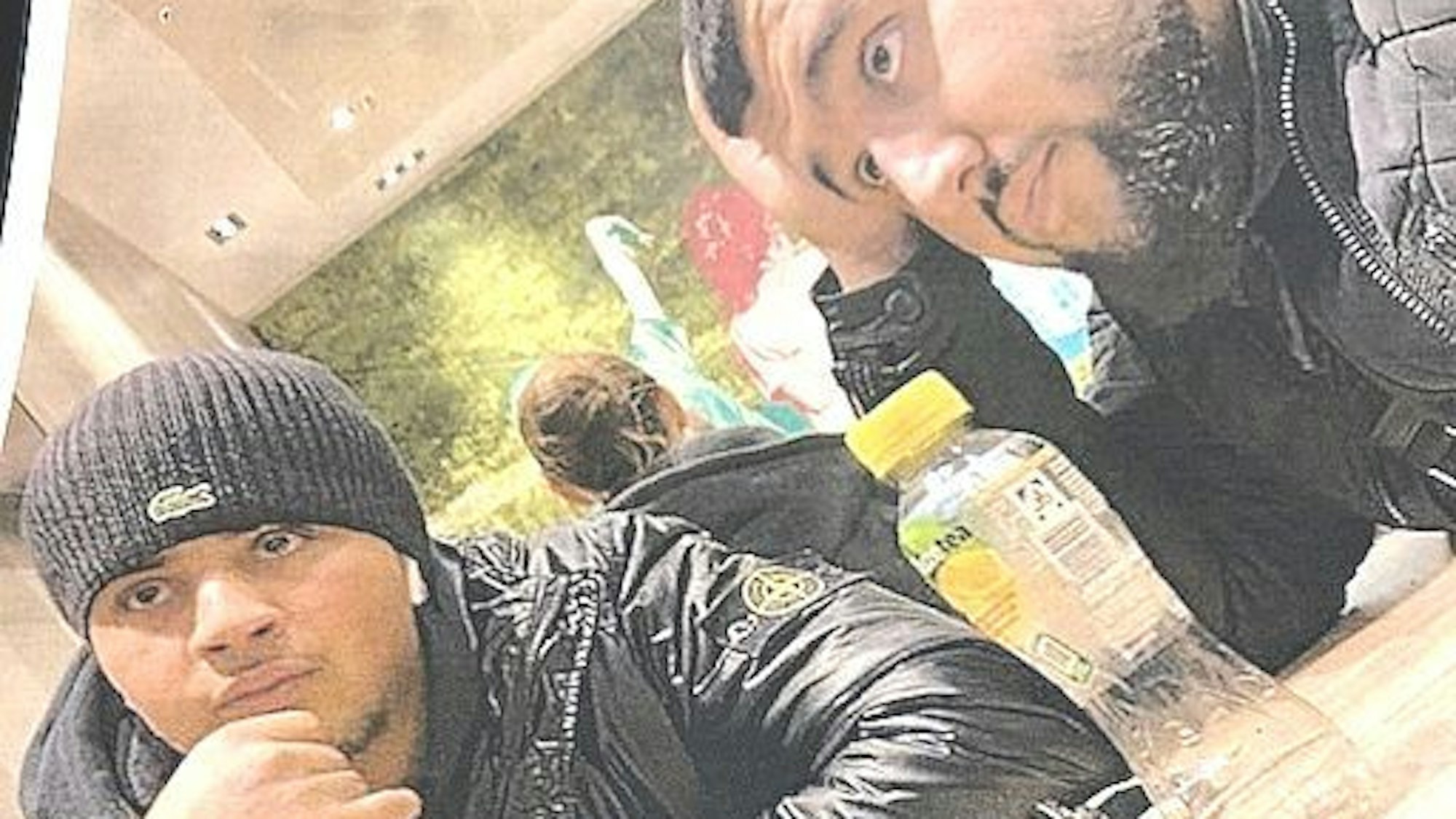 Zwei Männer mit dunkler Kleidung und dunklen Haaren sitzen an einem Tisch und stützen ihr Gesicht in ihre Hände.