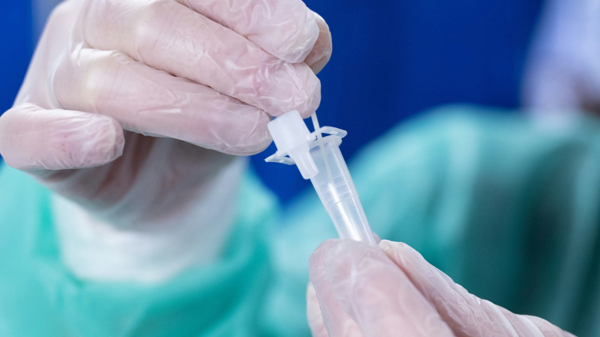 Ein Forscher rührt mit einem Wattestäbchen in einer Ampulle eines Coronatests. (Symbolbild)