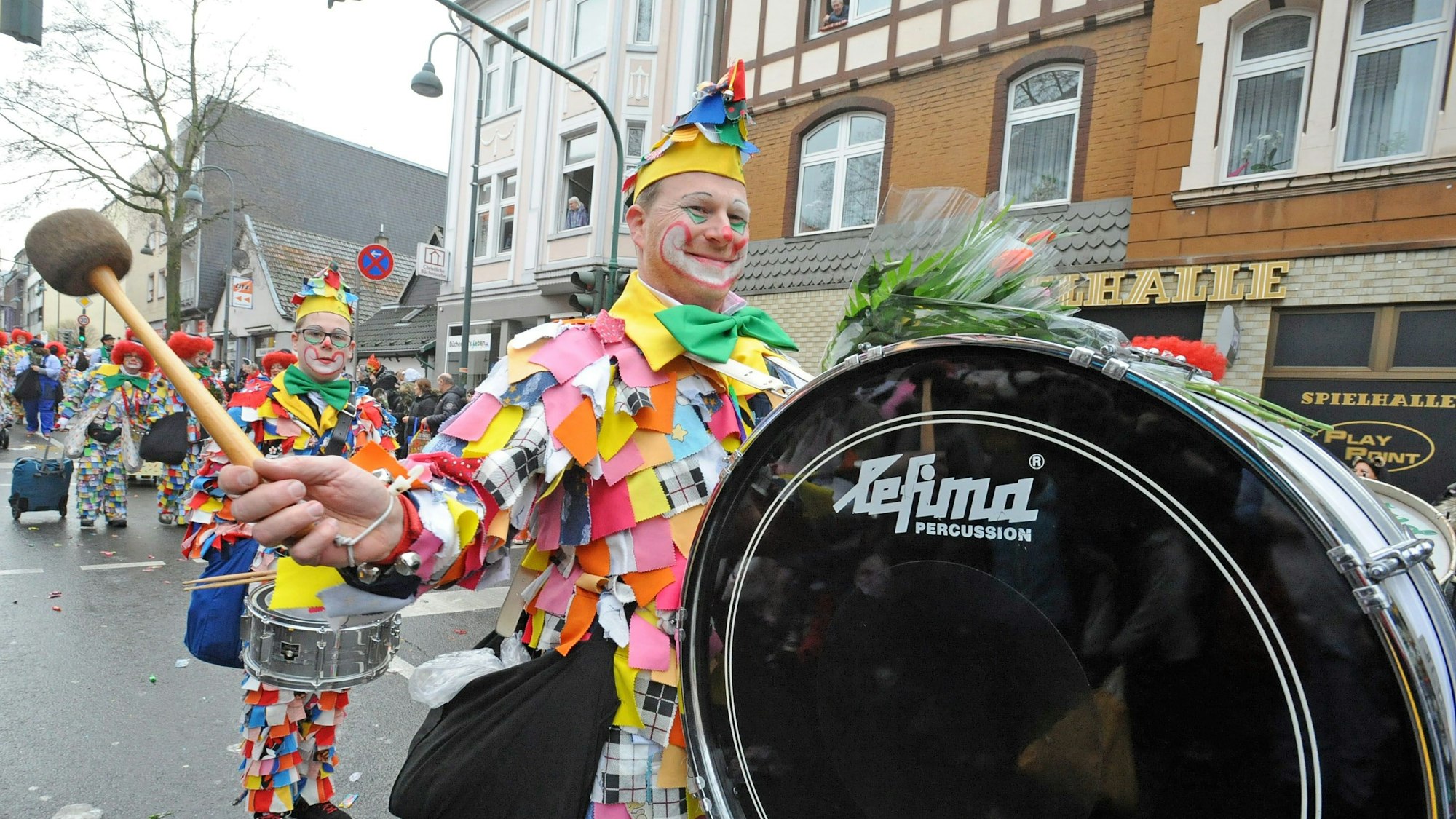 Ein Lappenclown schlägt auf eine decke Trumm (große Trommel) ein.