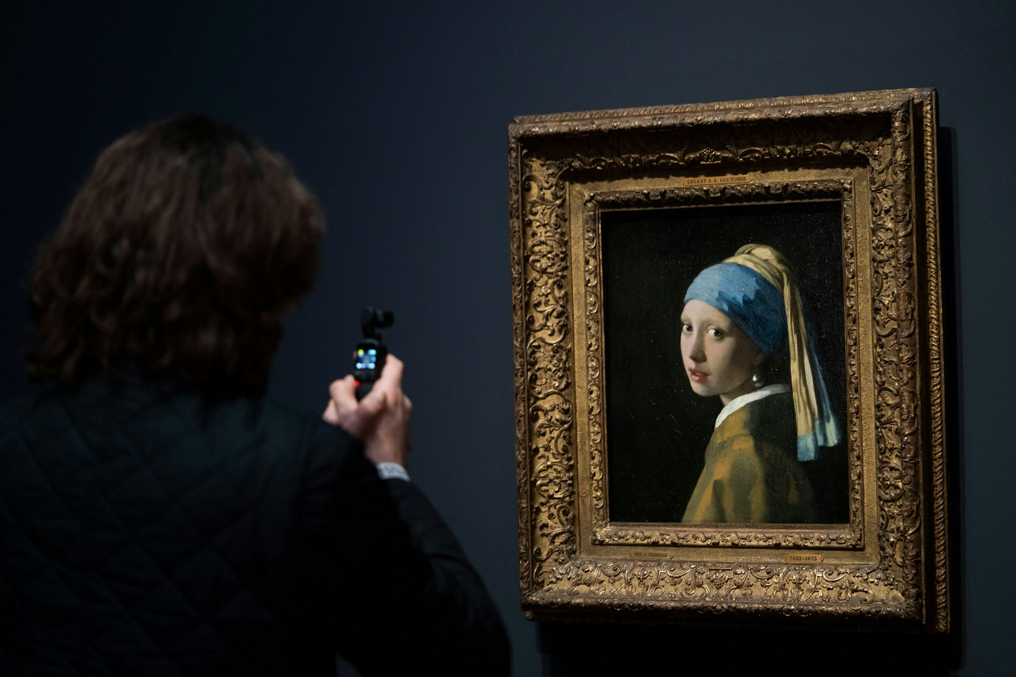 06.02.2023, Niederlande, Amsterdam: Eine Person fotografiert das Gemälde «Das Mädchen mit dem Perlenohrring» während eines Pressetermins für die Vermeer-Ausstellung im Amsterdamer Rijksmuseum.
