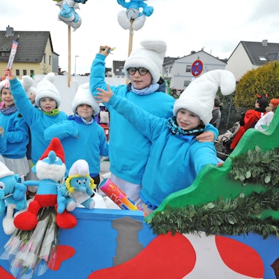 Als Schlümpfe verkleidete Kinder stehen auf einem Karnevalswagen.