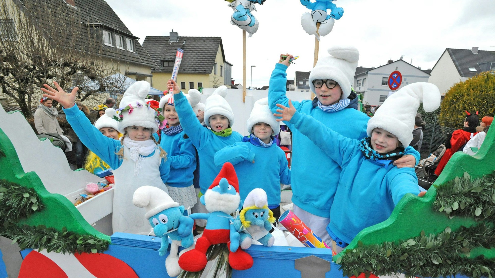 Als Schlümpfe verkleidete Kinder stehen auf einem Karnevalswagen.