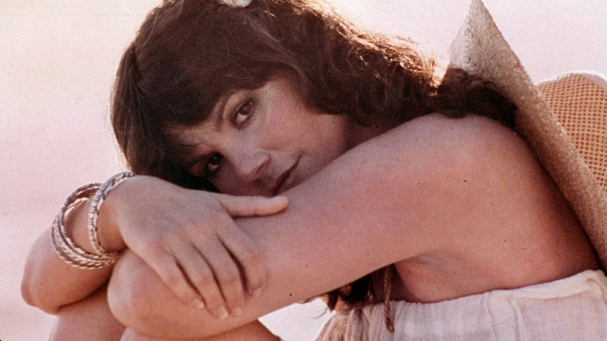 Linda Ronstadt schulterfrei, mit Hut auf dem Rücken.