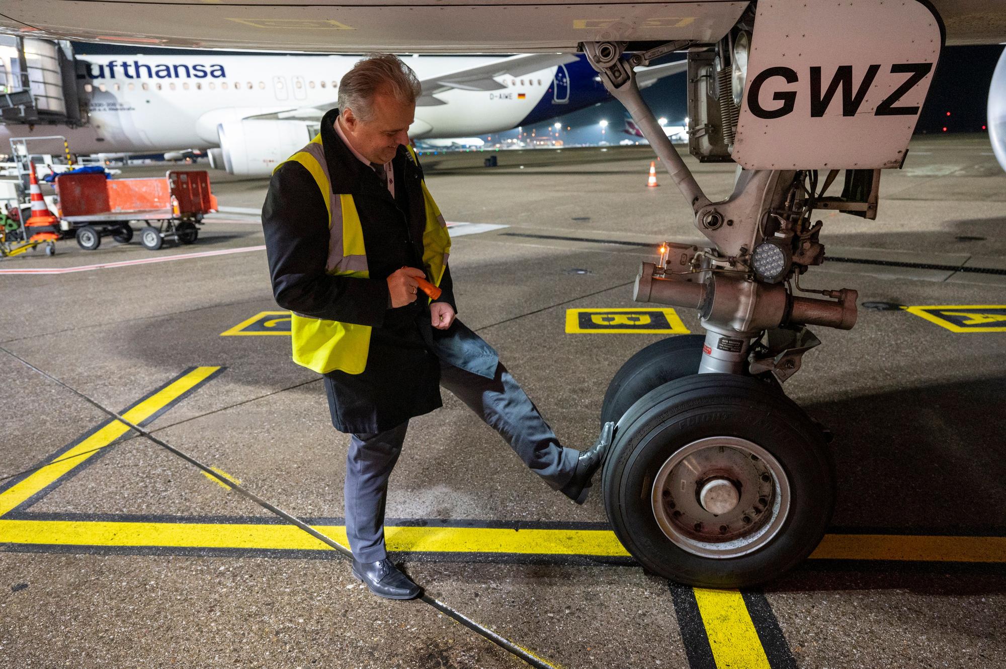 Flugkapitän Jan Will checkt das Flugzeug. Er prüft den Reifendruck mit den Füßen.