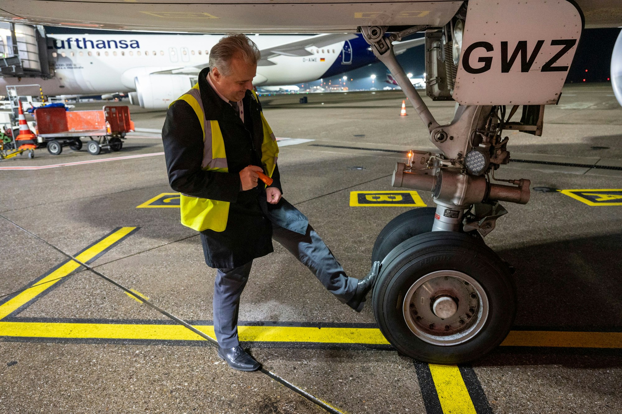Flugkapitän Jan Will checkt das Flugzeug. Er prüft den Reifendruck mit den Füßen.