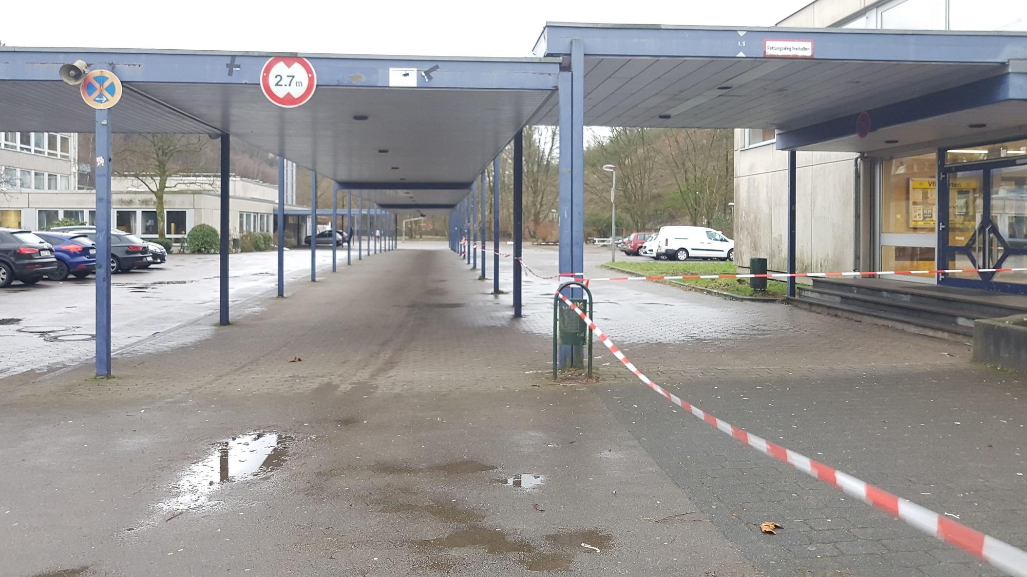 Blick auf ein Schulzentrum. Ein Absperrband flattert zwischen den Laubengängen. (Symbolbild)