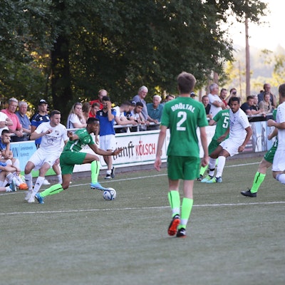 Auf einem Rasenplatz ist eine Spielszene im Fußball zu sehen.