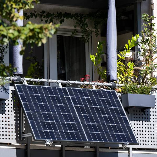 Eine kleine Solaranlage ist an einem Balkon eines Mehrparteienhauses angebracht.