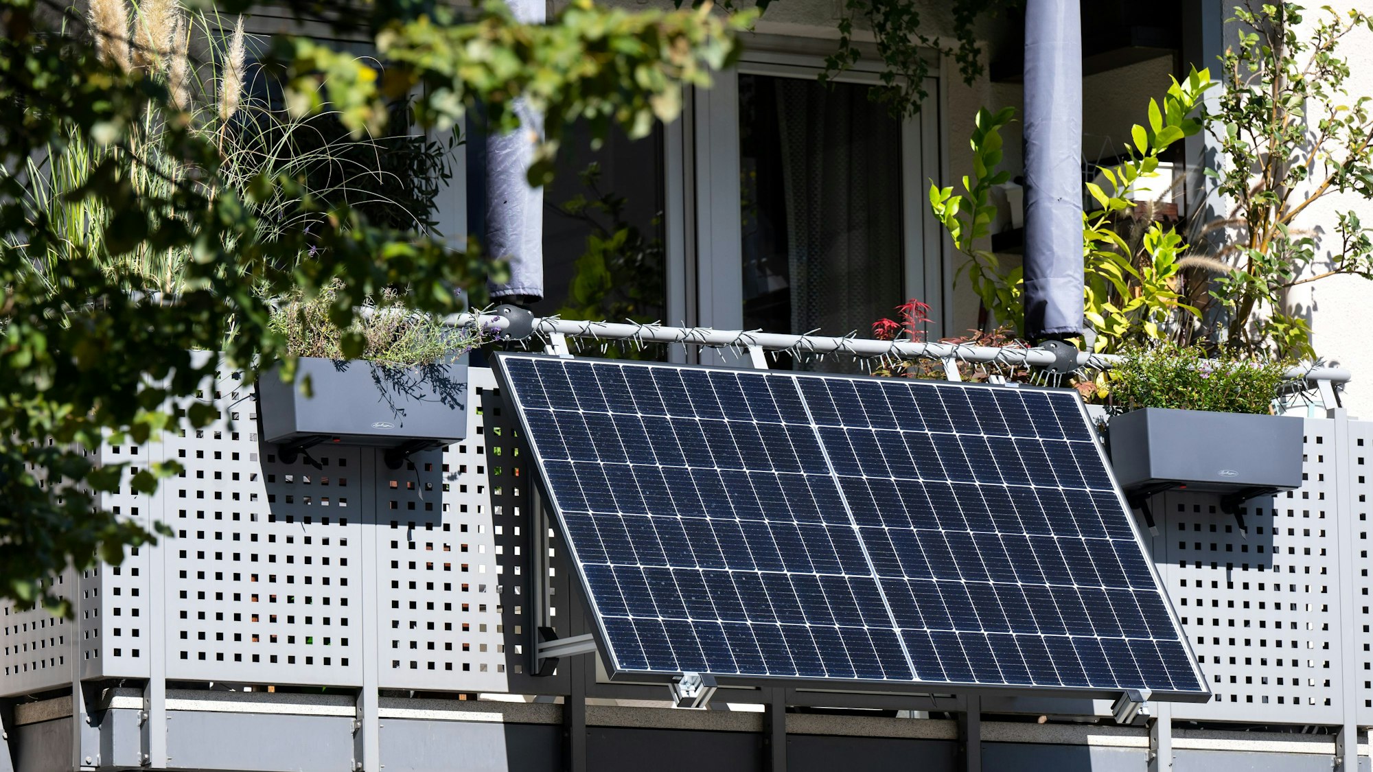 Eine kleine Solaranlage ist an einem Balkon eines Mehrparteienhauses angebracht.