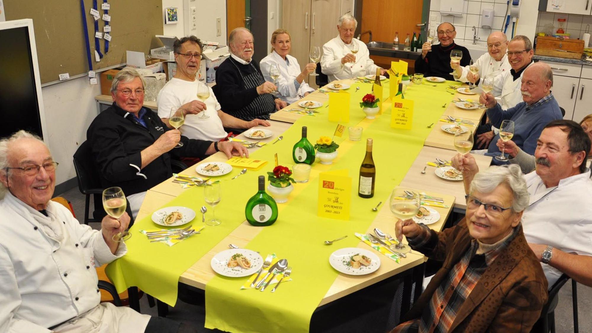 In fröhlicher Runde an der festlich geschmückten Tafel heben die Clubmitglieder ihre Weingläser.