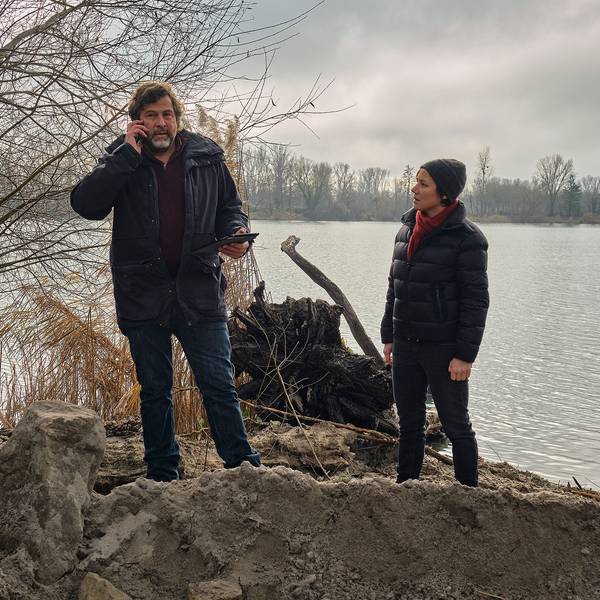 Die Kommissare Franziska Tobler (Eva Löbau) und Friedemann Berg (Hans-Jochen Wagner) stehen am Ufer eines Sees. Vor ihnen ist Erde aufgeschüttet.
