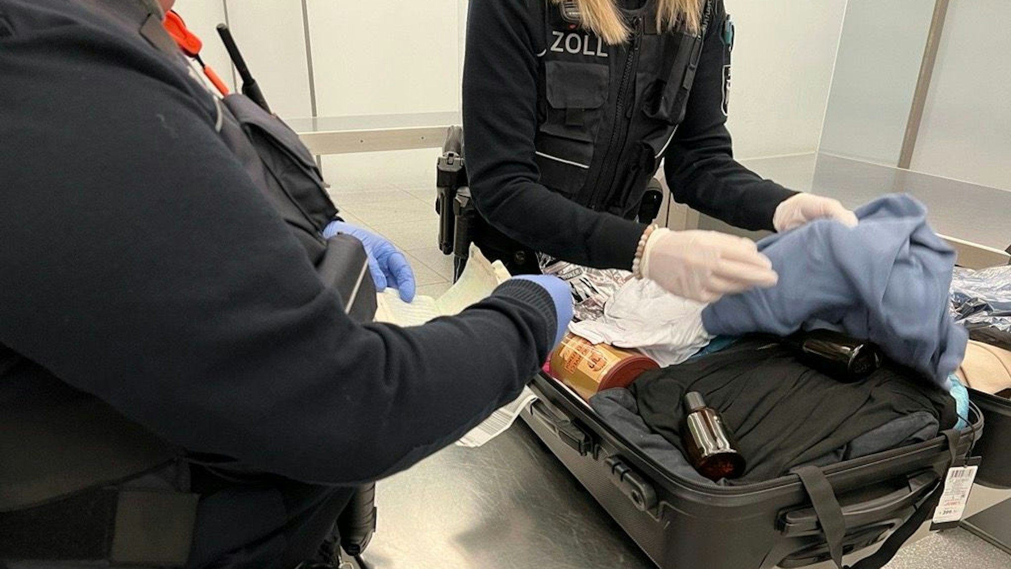 Zwei Zöllnerinnen durchsuchen einen Koffer.