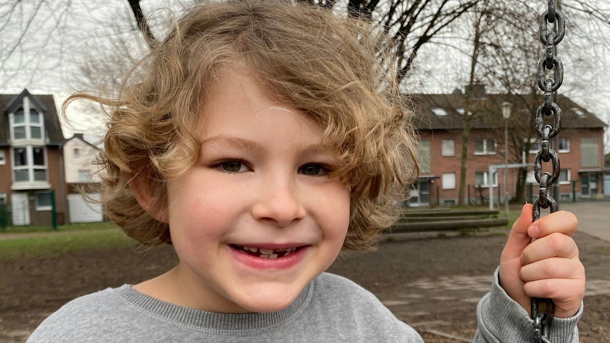 Der junge wir helfen-Spender Mats Berens sitz auf einer Schaukel und lacht.