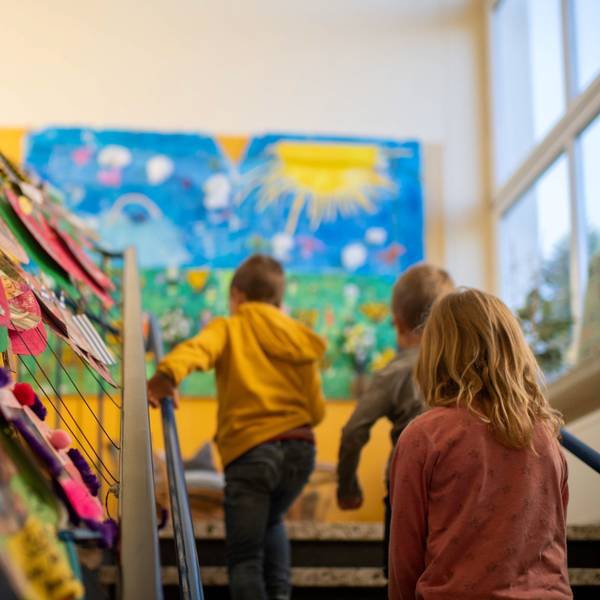 Für drei Monate sollen die Kindergärten der Kolpingstadt früher schließen und später öffnen. Das Foto zeigt Kinder in einer Einrichtung, sie gehen eine Treppe hinauf.