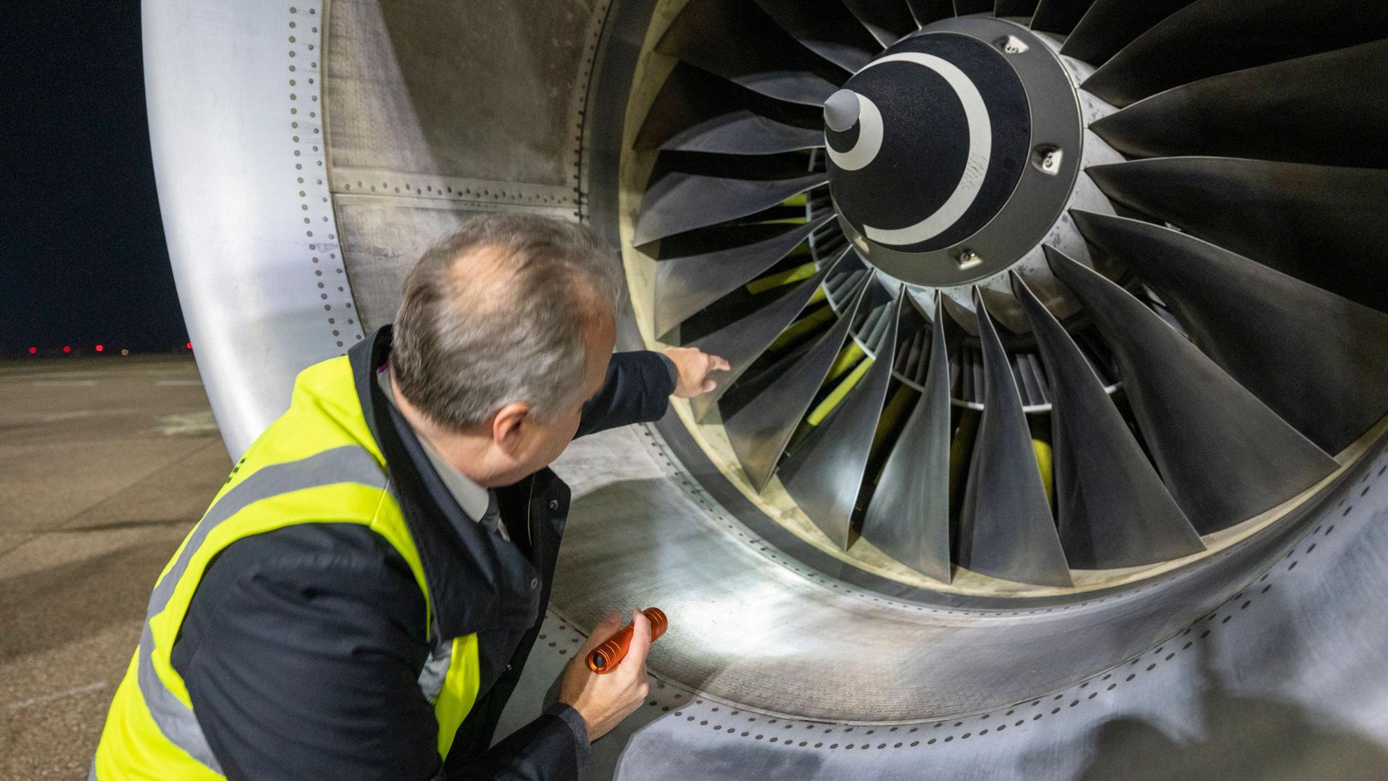 Flugkapitän Jan Will checkt das Flugzeug. Er leuchtet ins Triebwerk.