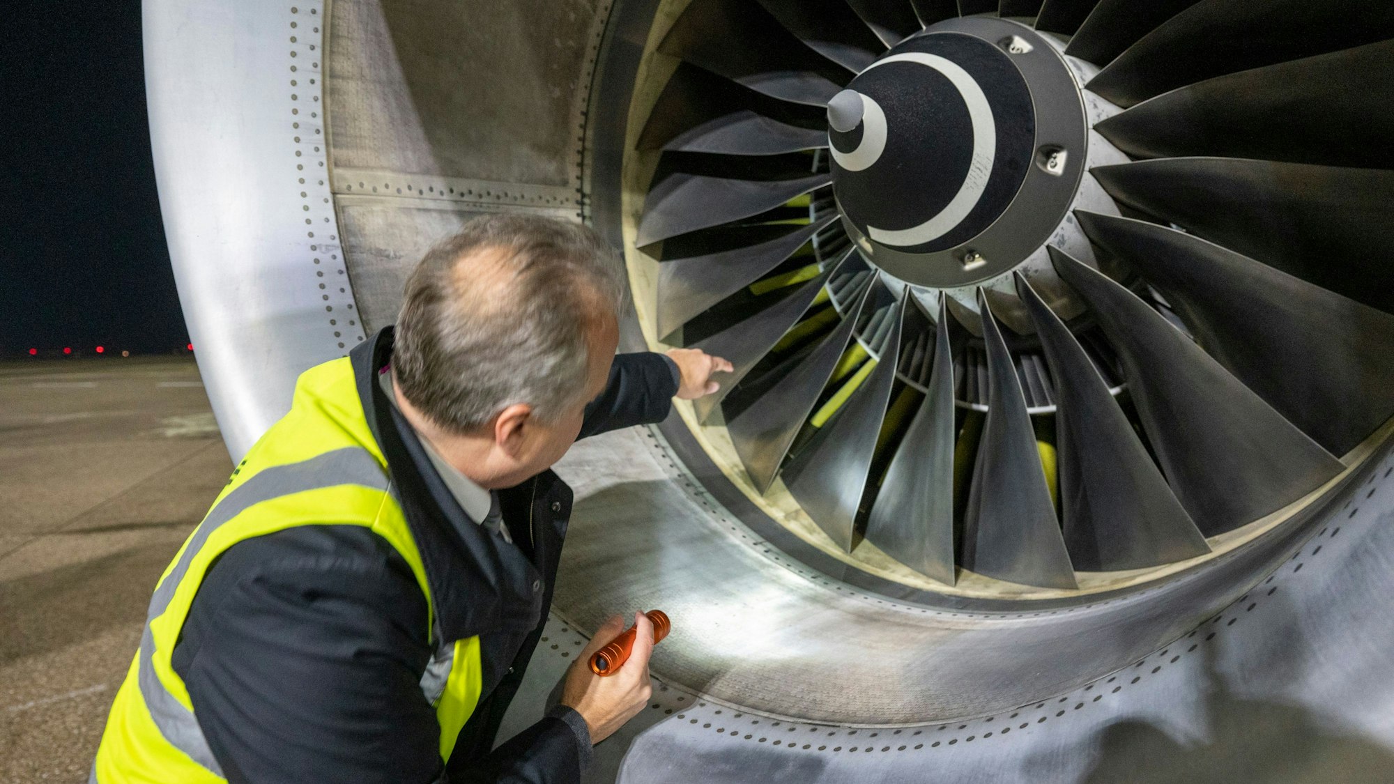 Flugkapitän Jan Will checkt das Flugzeug. Er leuchtet ins Triebwerk.