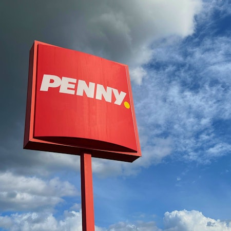 Dunkle Wolken und das rote Schild des Discounters Penny.