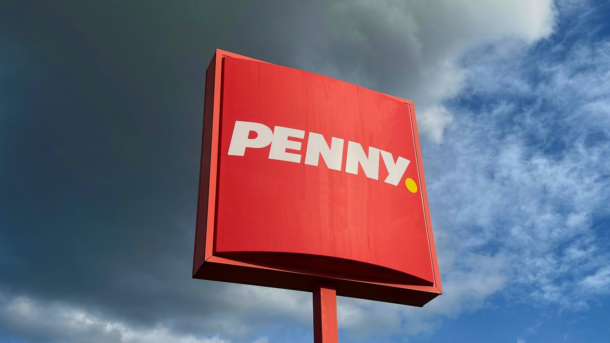 Dunkle Wolken und das rote Schild des Discounters Penny.