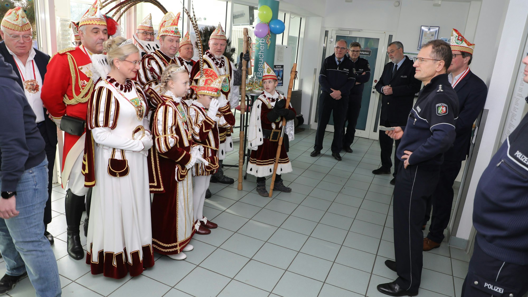 Mehrere führende Polizeibeamte stehen rechts im Foyer, das Kinderdreigestirn und das große Trifolium links.