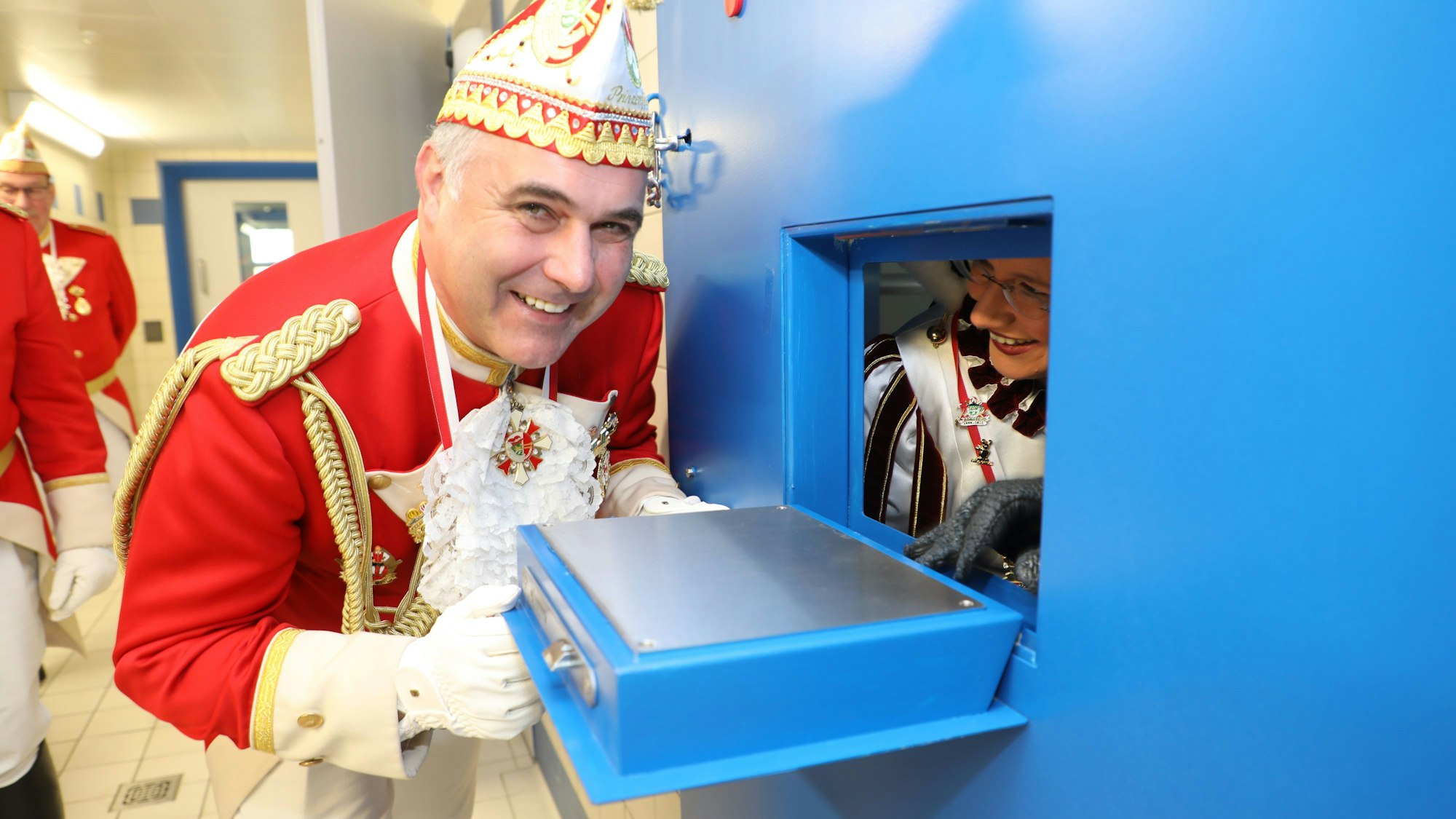 Prinzenführer Frank Mehren spricht mit dem Dreigestirn durch eine Klappe in der Zellentür des Polizeigewahrsams.