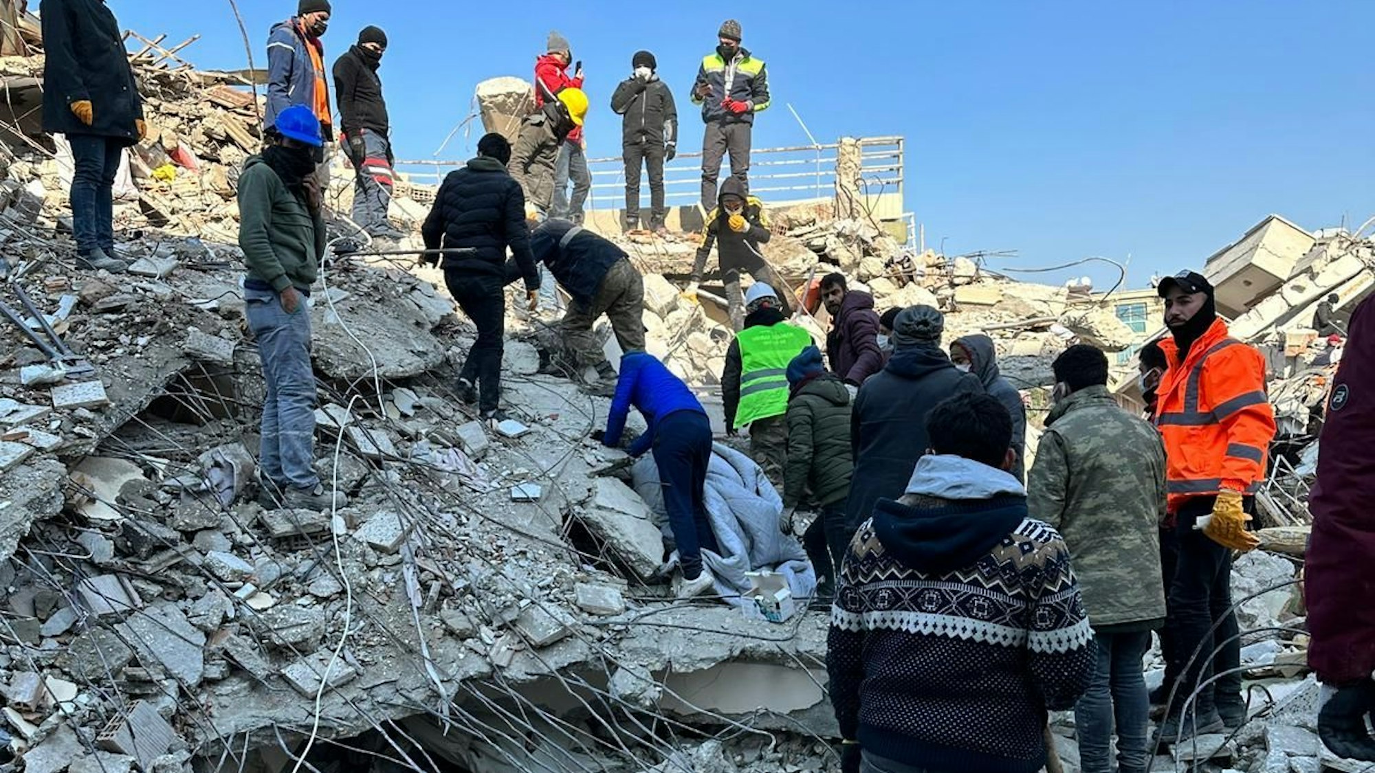 Helfer auf einem Trümmerberg in Hatay.