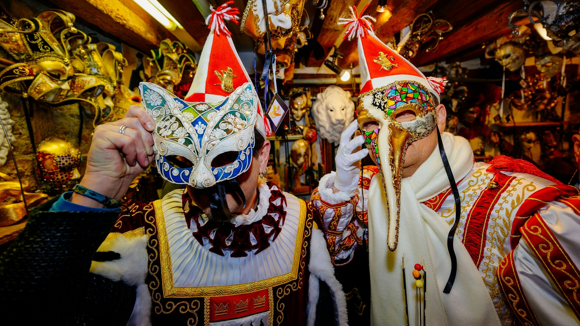 Prinz Boris I. (Boris Müller), Bauer Marco (Marco Schneefeld) halten sich beim Besuch in der Werkstatt eines Maskenbauer Masken vor ihren Gesichtern.