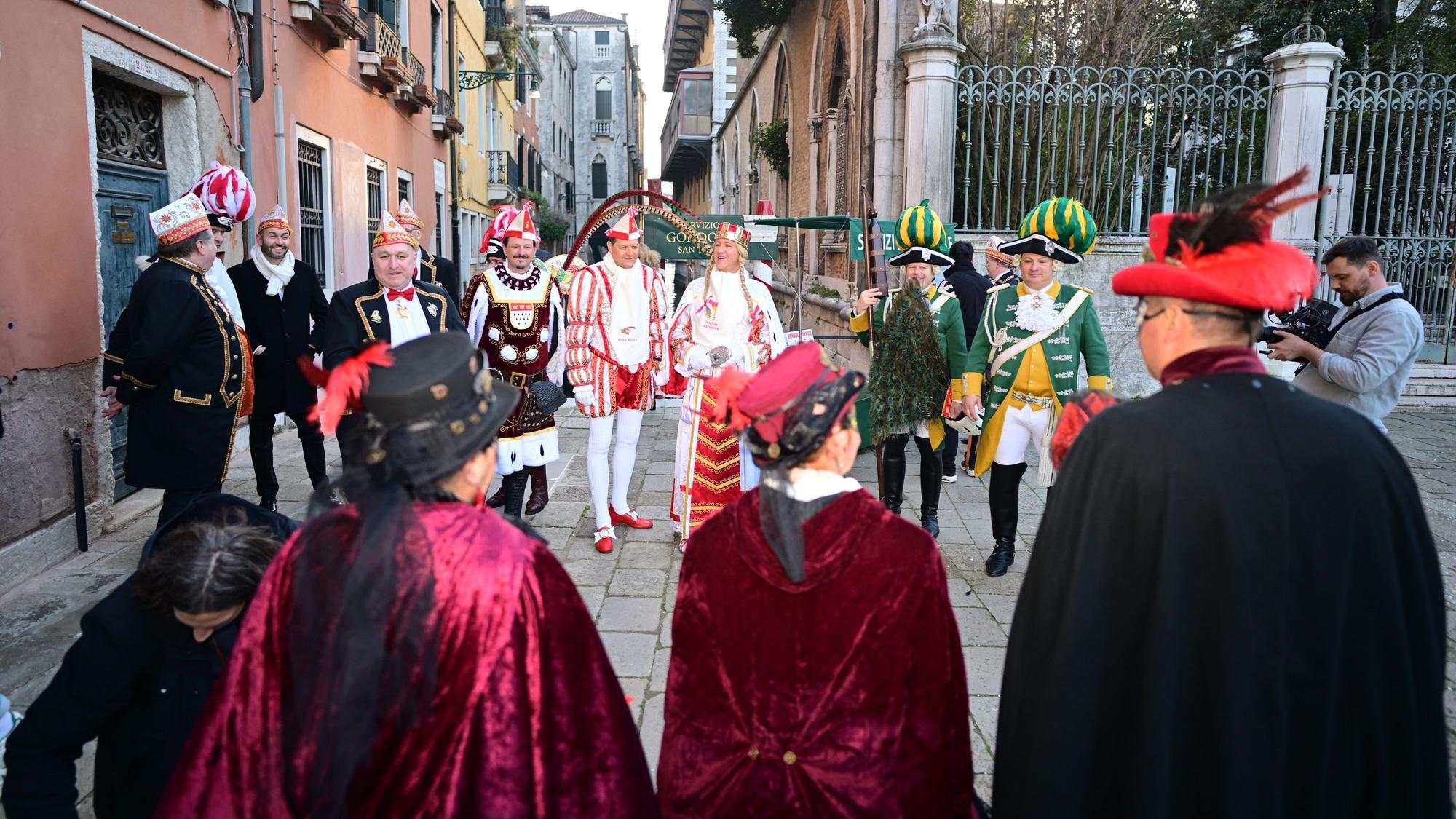 Das Kölner Dreigestirn steht mit mehreren Menschen in einer Gasse in Venedig.