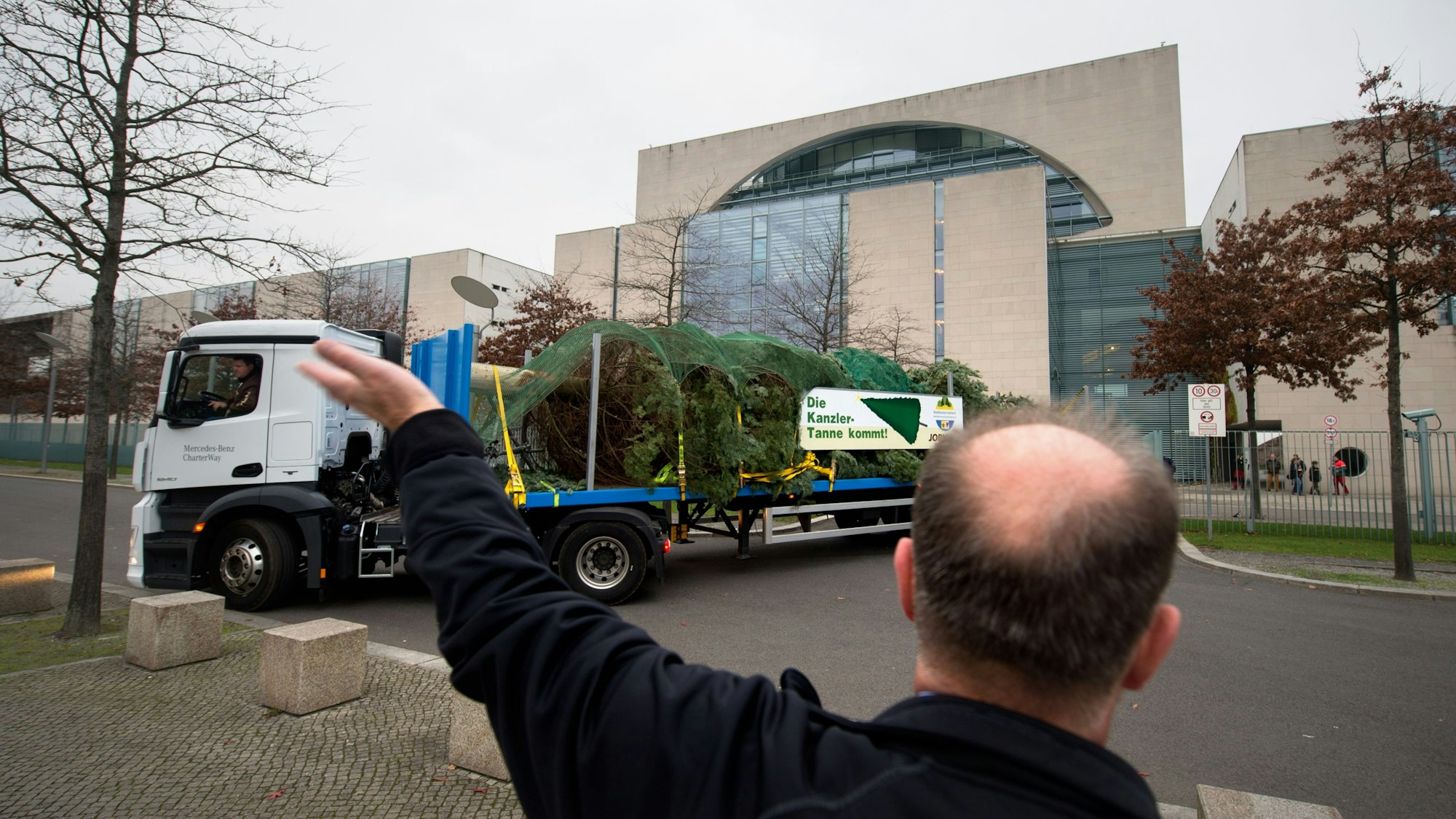 Ein LKW, der mit einem Weihnachtsbaum beladen ist, rangiert am 22.11.2014 rückwärts in die Einfahrt zum Kanzleramt in Berlin und wird von einem Helfer eingewiesen. Die 14,5 Meter hohe Küstentanne aus Mecklenburg-Vorpommern wird in den folgenden Tagen geschmückt und am 25.11. offiziell der Bundeskanzlerin Merkel übergeben. Foto: Matthias Balk/dpa ++ +++ dpa-Bildfunk +++