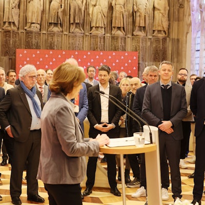 Henriette Reker steht am Rednerpult und die Gäste hören ihr zu.