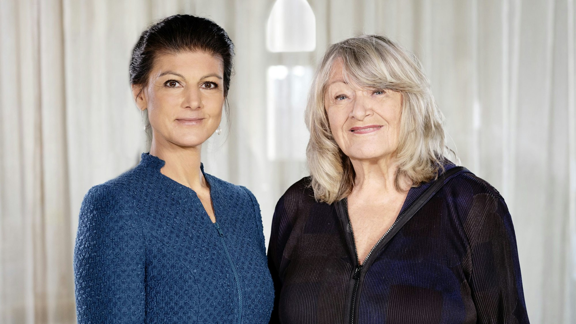 Sahra Wagenknecht und Alice Schwarze stehen nebeneinander und blicken freundlich in die Kamera.