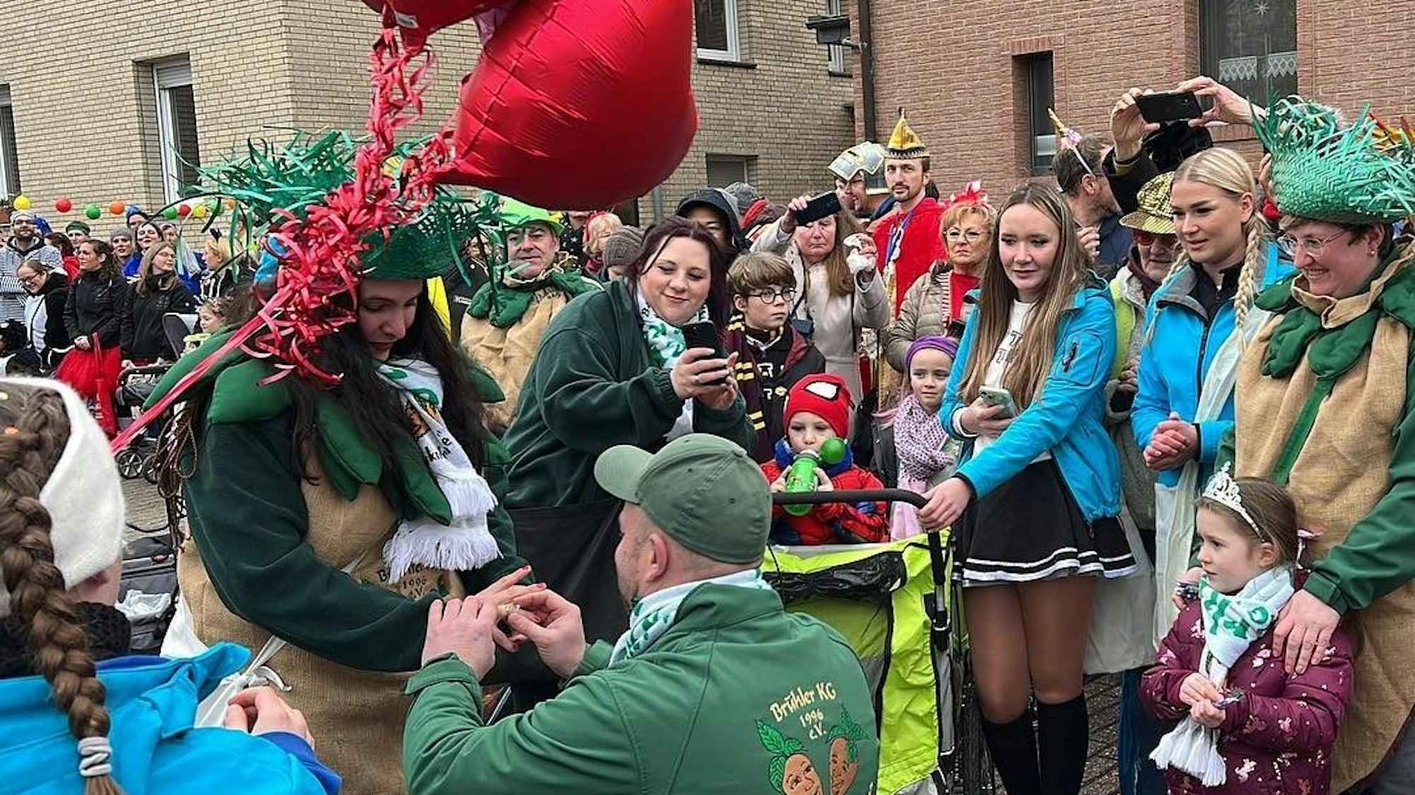 Es ist das Pärchen zu sehen. Um sie herum stehen viele verkleidete Menschen.