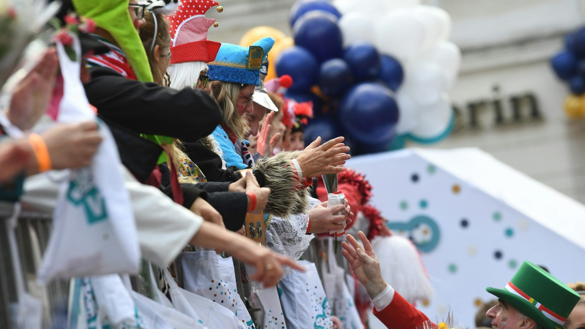 Karnevalisten auf dem Wagen verteilen Kamelle und Blumensträuße