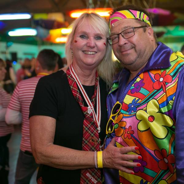 Ein als Schottin und Hippie kostümiertes Pärchen lächelt gemeinsam in die Kamera.