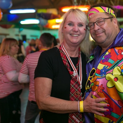 Ein als Schottin und Hippie kostümiertes Pärchen lächelt gemeinsam in die Kamera.