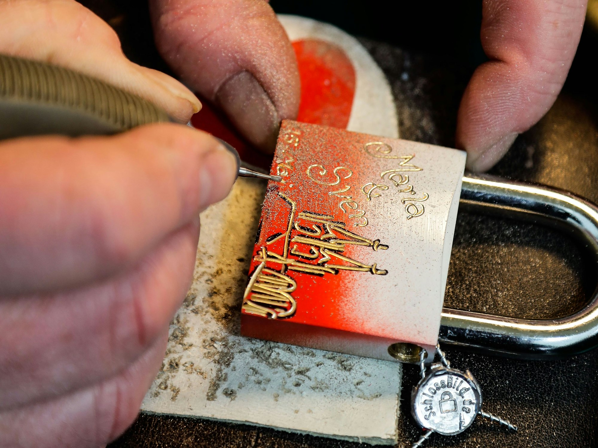 Liebesschloss-Künstler Peter Krahn graviert die Namen von Marla Carus und Sven Turi und den 15. Mai auf das Schloss ein.