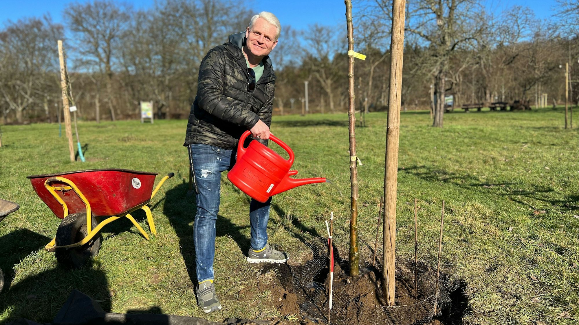Guido Cantz gießt einen Apfelbaum der Sorte Schick's Rheinischer Landapfel auf der Obstwiese auf Gut Leidenhausen im Kölner Stadtteil Porz-Eil.