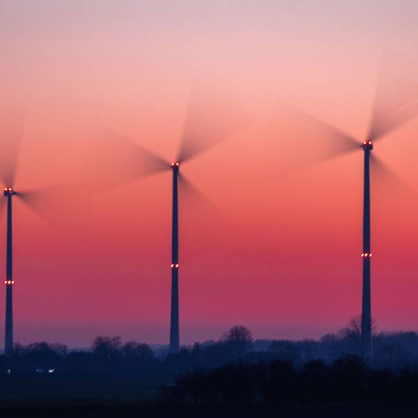 Die Rotoren von Windkraftanlagen drehen sich nach Sonnenuntergang. (Aufnahme mit langer Belichtungszeit)