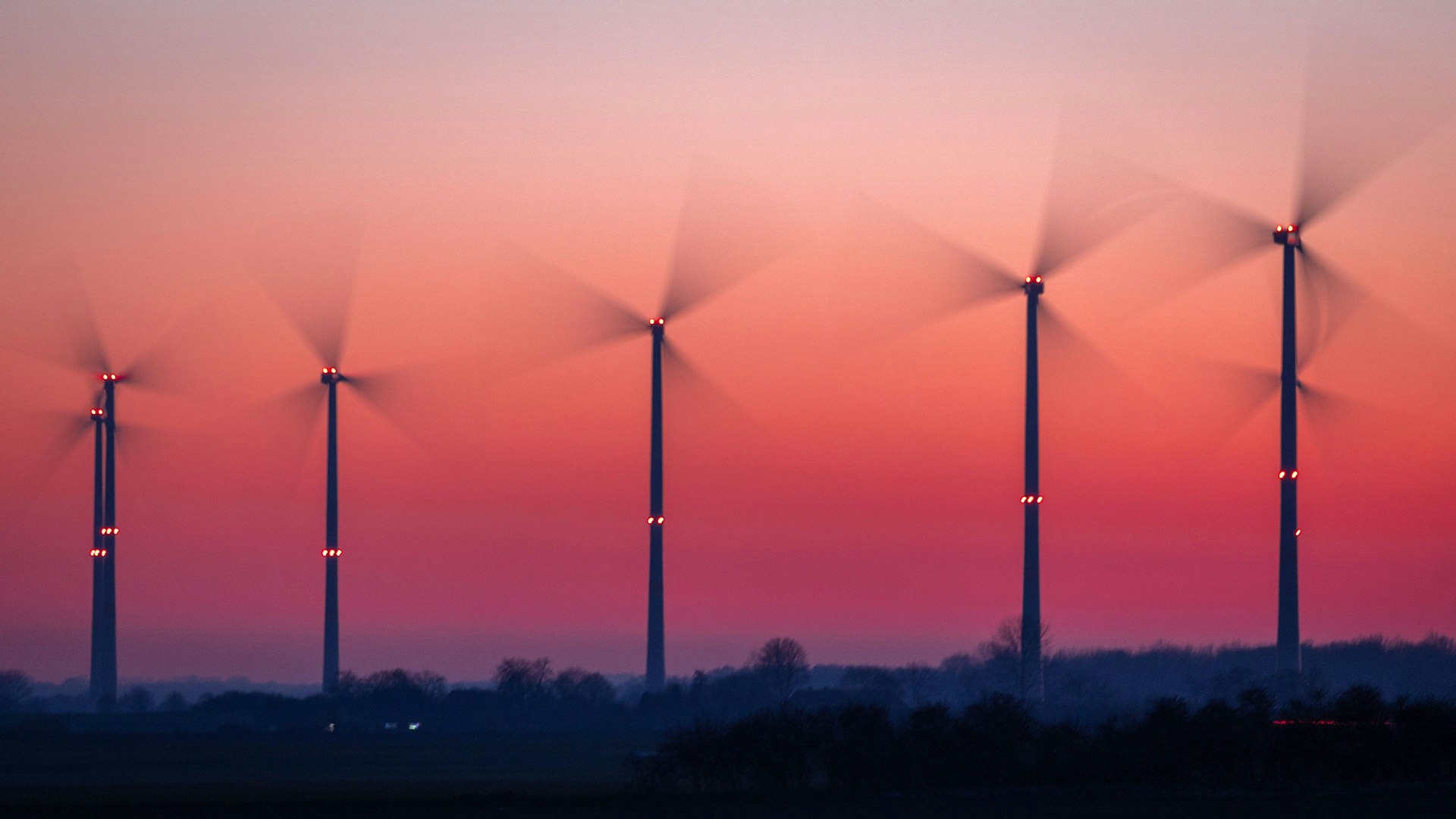 Die Rotoren von Windkraftanlagen drehen sich nach Sonnenuntergang. (Aufnahme mit langer Belichtungszeit)