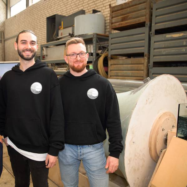 Köln-Business-Geschäftsführer Manfred Janssen mit Felix Roder und Marcel Heilich von „Rheinsharing“ stehen vor dem Prototyp des Kraftwerks. Sie lächeln in die Kamera.
