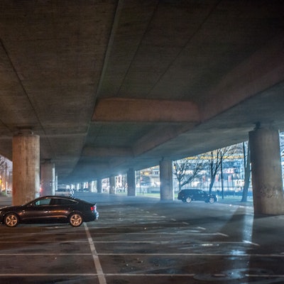 Nachtaufnahme unter der Stelzenautobahn. Ein einzelnes Auto steht auf dem Parkplatz unter der Stelze.