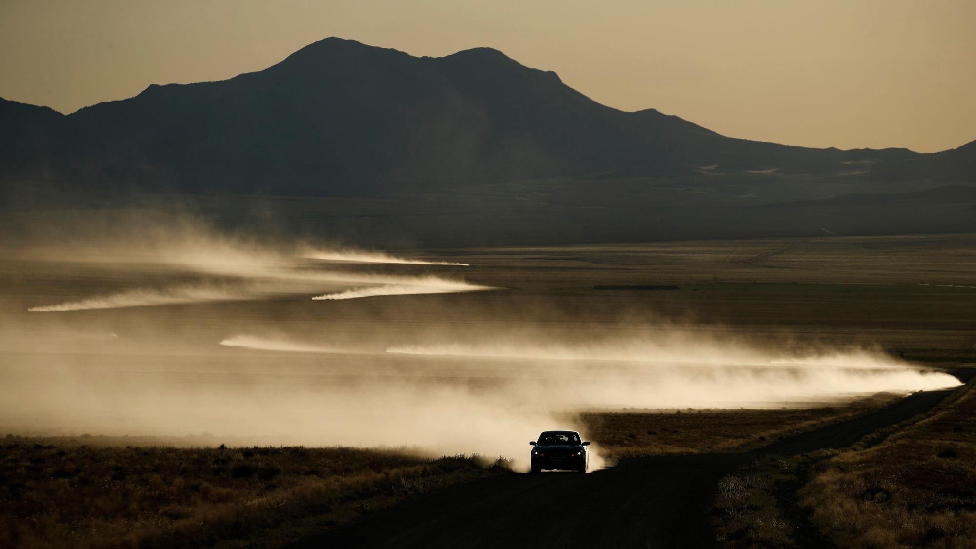 USA, Rachel: Autos hinterlassen eine in der Sonne glänzende Staubspur.