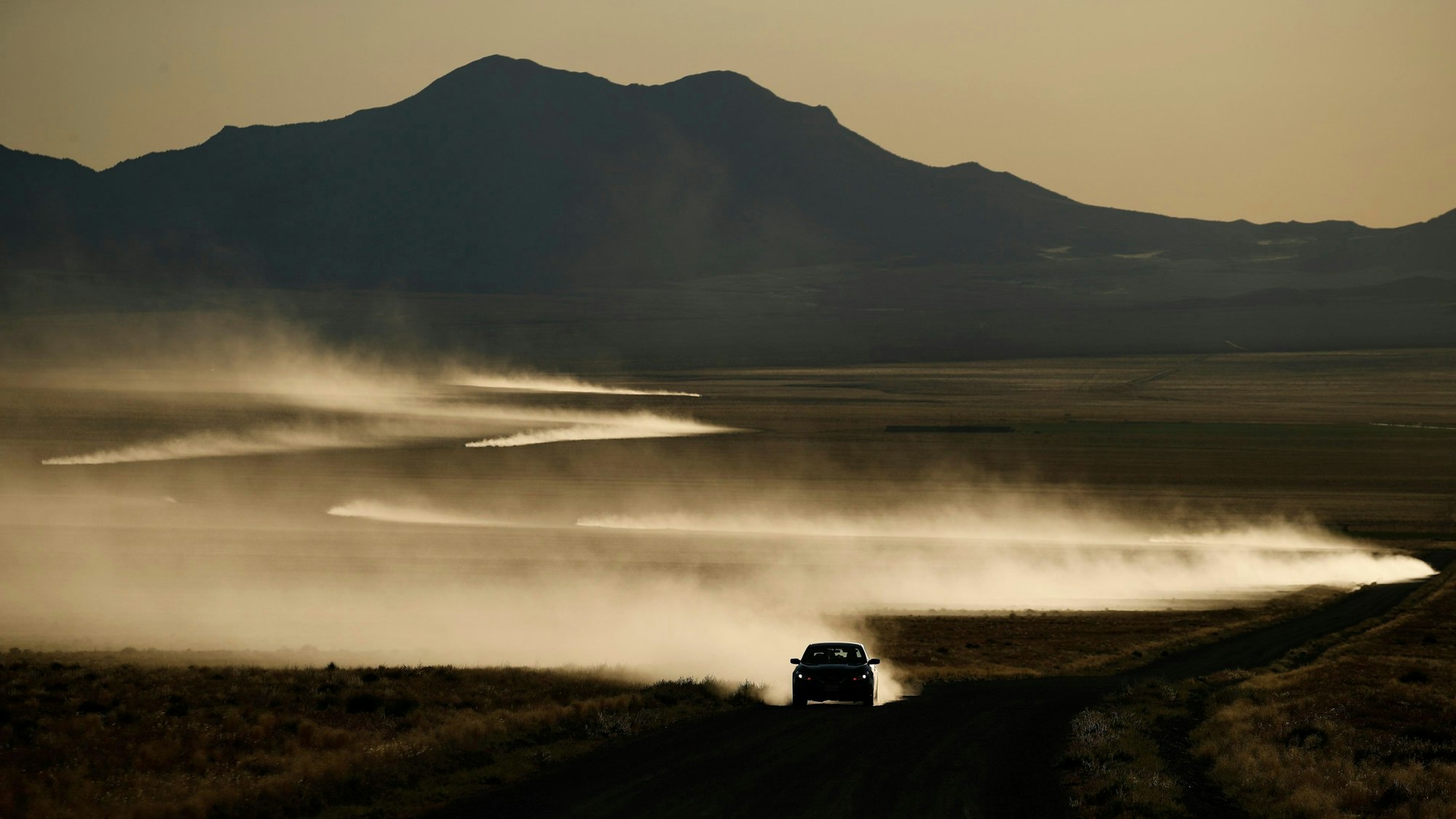 USA, Rachel: Autos hinterlassen eine in der Sonne glänzende Staubspur.