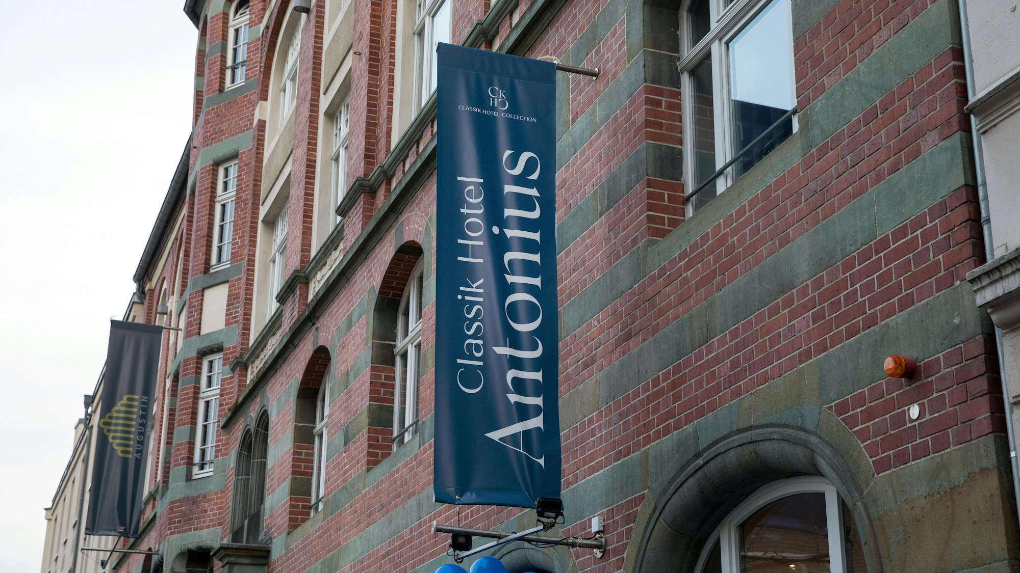 Die Backsteinfassade des Hotels mit einer blauen Flagge und blauen Luftballons