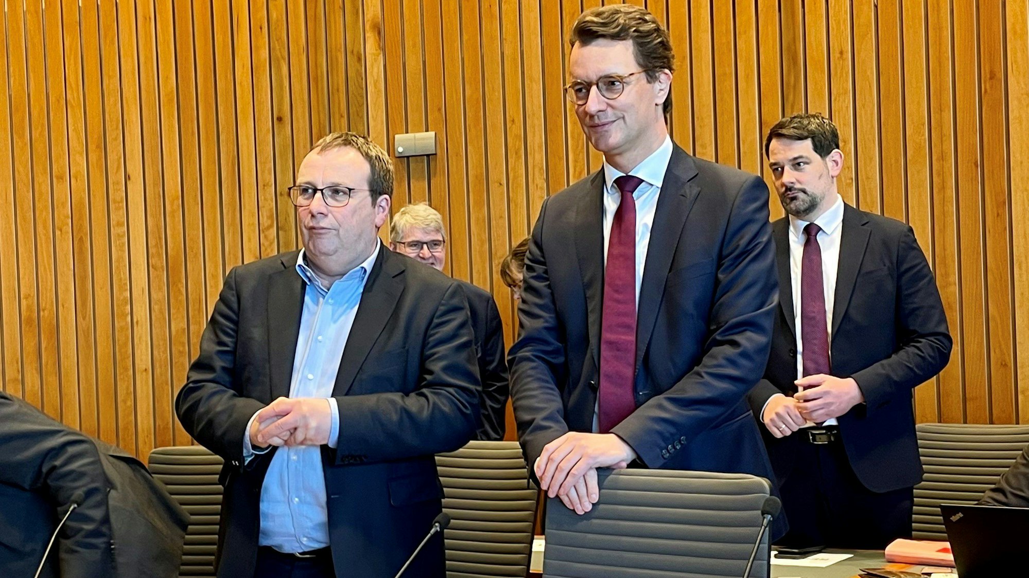Verkehrsminister Oliver Krischer (Bündnis 90/Die Grünen, l) und Nordrhein-Westfalens Ministerpräsident Hendrik Wüst (CDU, vorne rechts) kommen zu einer Sondersitzung des Verkehrsausschusses in den NRW-Landtag. Beide stehen noch hinter den Sitzen, auf denen sie gleich Platz nehmen werden. Wüst trägt Anzug und Krawatte, Krischer auch einen dunklen Anzug und geöffneten Kragen.