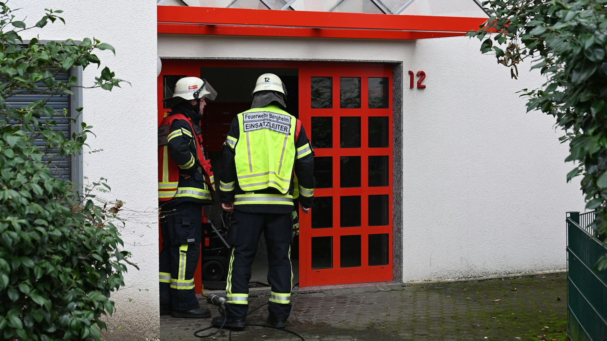 Zwei Feuerwehrleute stehen vor dem Eingang eines Hauses in Ahe.